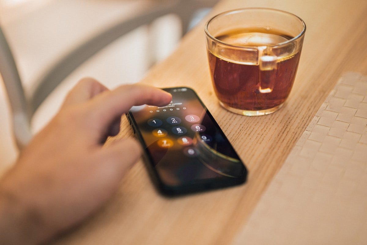 Person calmly setting up their phone next to a cup of coffee