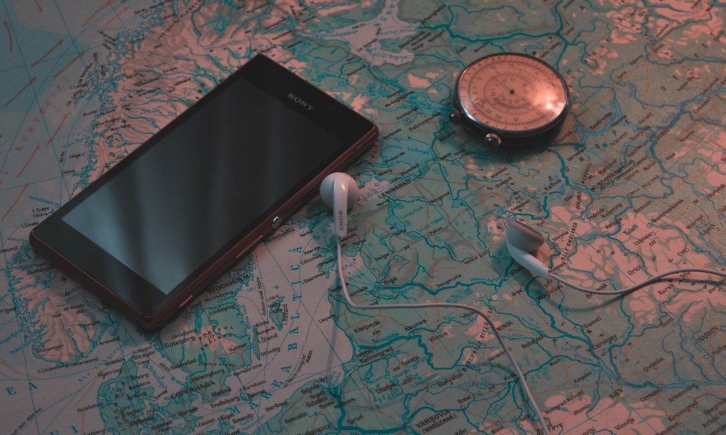 Smartphone resting on a travel map with earphones while planning a trip
