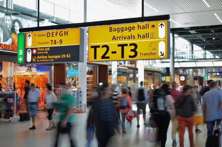 Travellers walking through an airport arrivals and baggage hall after landing