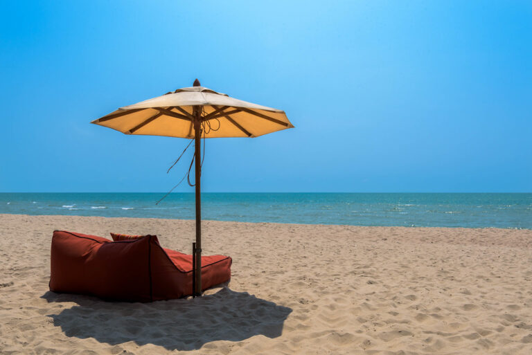 Beach umbrella and lounger beside a blue sea on a sunny day